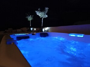 A hot tub with a blue light, surrounded by rocks and two illuminated trees. - Charming gîte with jacuzzi facing Mont Ventoux (CRESTET)