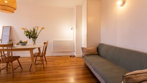 Een eetgedeelte met een tafel, stoelen, een vaas met bloemen en een wandlamp.
