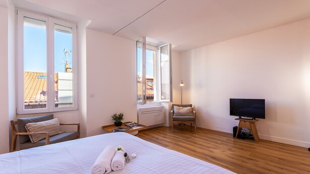 Een slaapkamer met een groot bed, een televisie, een stoel en een raam.