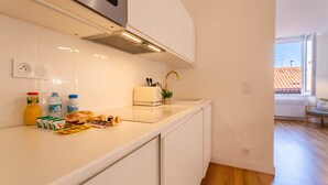 Een moderne keuken met witte kasten, een roestvrijstalen afzuigkap en een raam met uitzicht op een woonwijk.
