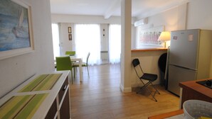 A compact kitchen with a refrigerator, a dining table with chairs, and a small seating area with a chair. - Palais Rouaze/ Beg4012/ 2P (Cannes)