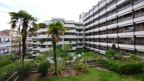 Un immeuble à plusieurs étages doté de balcons, entouré de verdure et agrémenté d’un petit jardin.