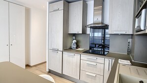 Una cocina moderna con armarios de madera clara, una campana extractora de acero inoxidable y un horno empotrado.
