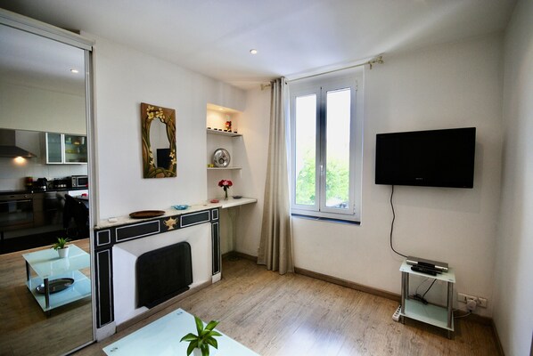 Una cocina moderna con chimenea, un comedor con mesa de vidrio y un televisor montado en la pared.