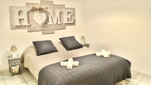 Ein Schlafzimmer mit einem Bett, zwei Nachttischen, Wandkunst und einer Lampe.