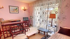 A room with a bed, a table with chairs, a desk, a lamp, and a fan. - WINDSOR/DET2002-1/bed (Cannes)