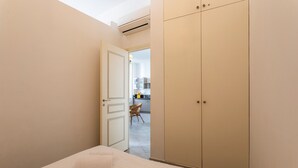 Una camera da letto con un letto, un armadio e una porta aperta che dà su un angolo cottura.