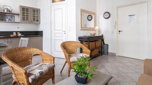 Una cucina moderna con una porta bianca, sedie in vimini, una pianta in vaso e un tavolo da pranzo.