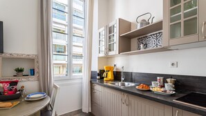 Una cucina con finestra, lavello, macchina del caffè e zona pranzo con tavolo e sedie.