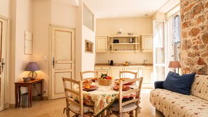 Un comedor con una mesa dispuesta para cuatro, un sofá y una cocina al fondo.