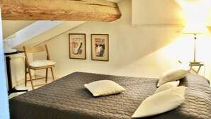 Een kamer met een bed, een stoel en twee foto's in lijsten aan de muur.