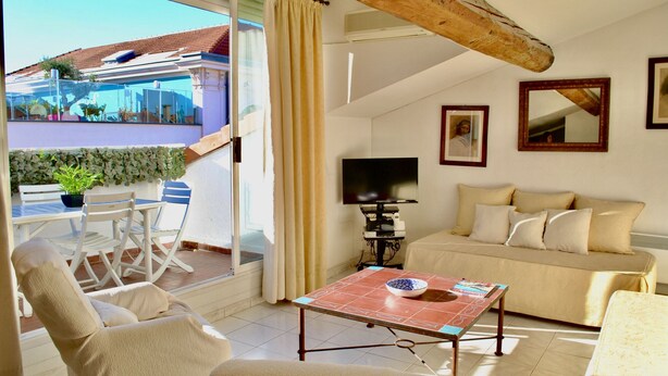 Een woonkamer met een bank, een televisie, een tafel met een schaal en een balkon met uitzicht.