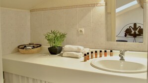 Een badkamer met een wastafel, spiegel, handdoekhouder en een potplant.