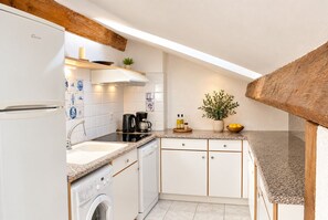 A compact kitchen with a washing machine, a coffee maker, and a sink.