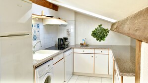 Een keuken met een wasmachine, een spoelbak, een koffiezetapparaat en een potplant.