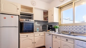 A kitchen with white cabinets, a refrigerator, an oven, a microwave, a dishwasher, and a washing machine. - Appartement Trois pièces DEB5515 (Cannes)