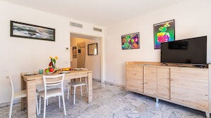 A dining area with a wooden table, white chairs, a TV, and artwork on the walls. - Appartement Trois pièces DEB5515 (Cannes)