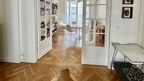 A room with a wooden herringbone floor, a cowhide rug, a dining table with chairs, and a ceiling light fixture. - Riviera Design / Charming apartment 2mn from the beach (Cannes)