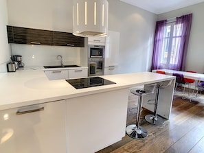 A modern kitchen with a central island, built-in appliances, and a dining area with bar stools.