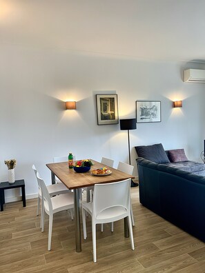 Een moderne woonruimte met een eettafel, stoelen, een bank en een vloerlamp.