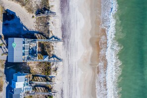 An aerial view of a coastal area with a beach, a parking lot, and a building with a roof terrace. - Rejuvenate! Full 4Plex Oceanfront Rental w/ Views | Pool | 4 Hot Tubs | Elevator (North Topsail Beach)
