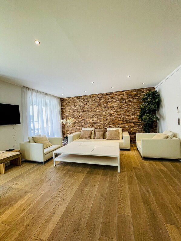 A modern living room with a stone wall, a white sofa, a coffee table, and wooden flooring.