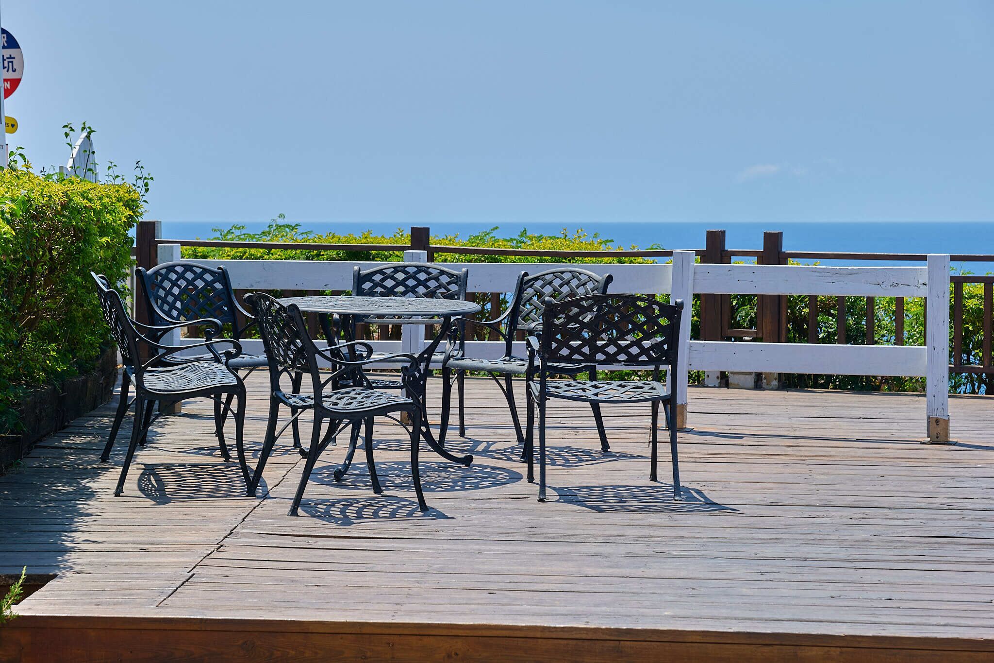 A wooden deck with outdoor furniture and a view of the ocean.