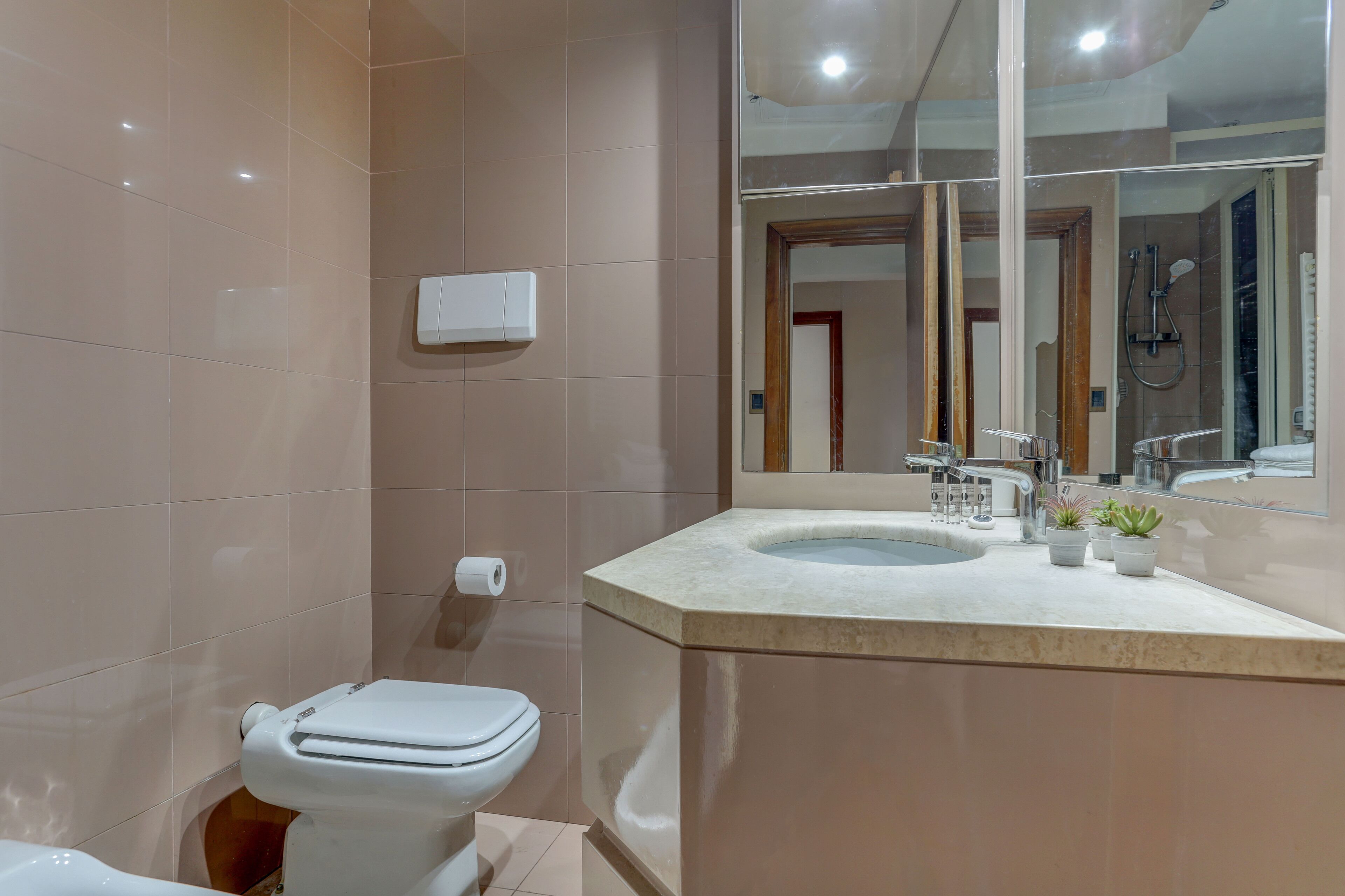 A modern bathroom with a toilet, sink, and mirror.