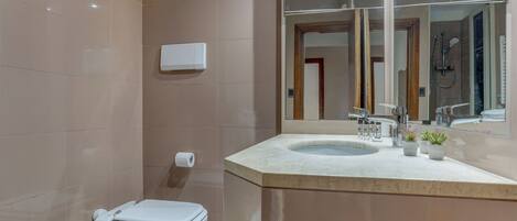 A modern bathroom with a toilet, sink, and mirror.