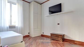 Une chambre à coucher comprenant un lit, une armoire, un téléviseur fixé au mur et un meuble en bois.