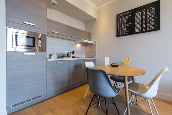 A modern kitchen with a built-in microwave, a stainless steel oven, and a wall-mounted digital departure board.