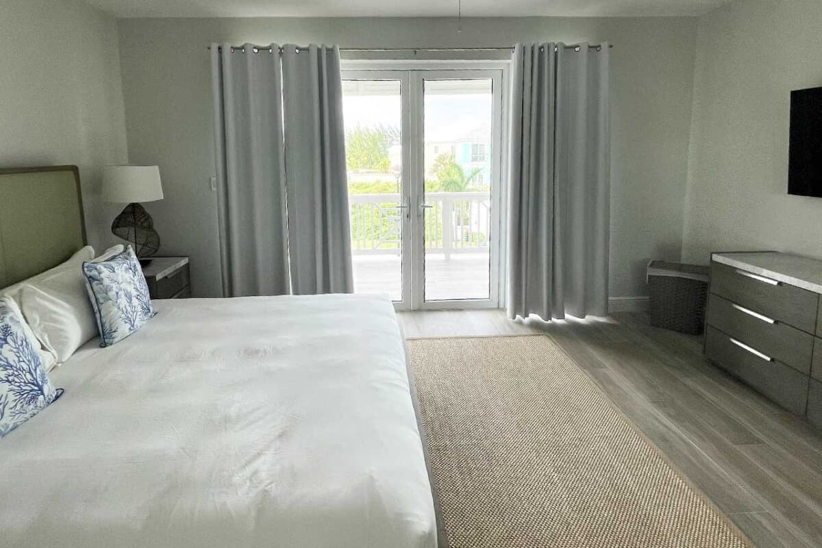 Een hotelkamer met een bed, nachtkastje, dressoir en een plafondventilator.