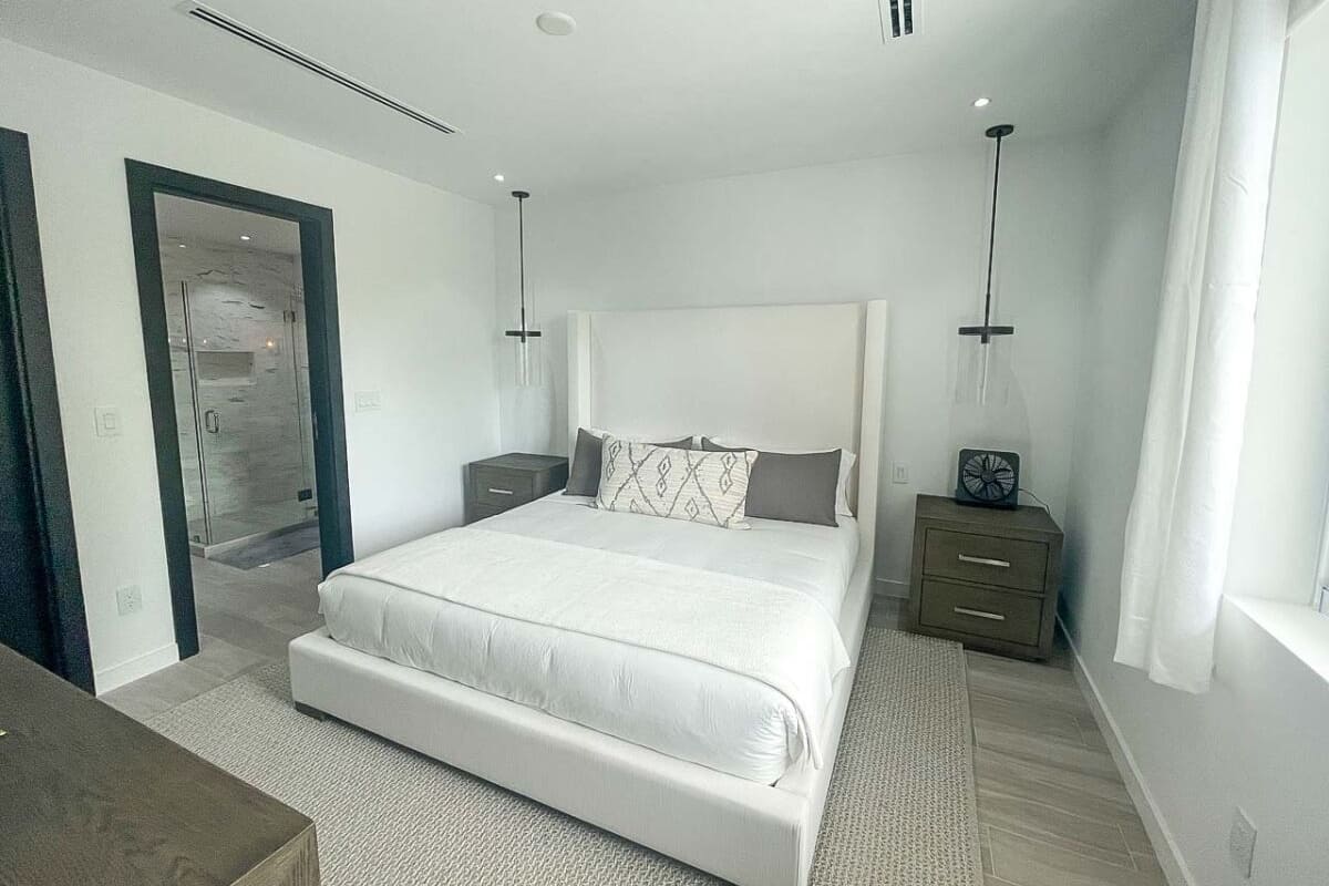 Een moderne slaapkamer met een groot bed, nachtkastjes en een inloopkast.