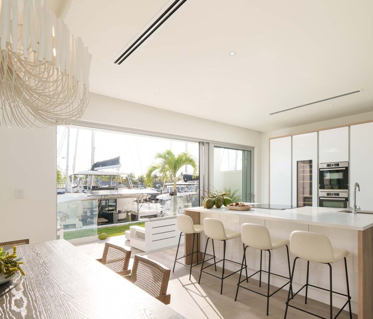A modern kitchen with a large island, bar stools, and a view of a marina.