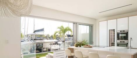 A modern kitchen with a large island, bar stools, and a view of a marina.