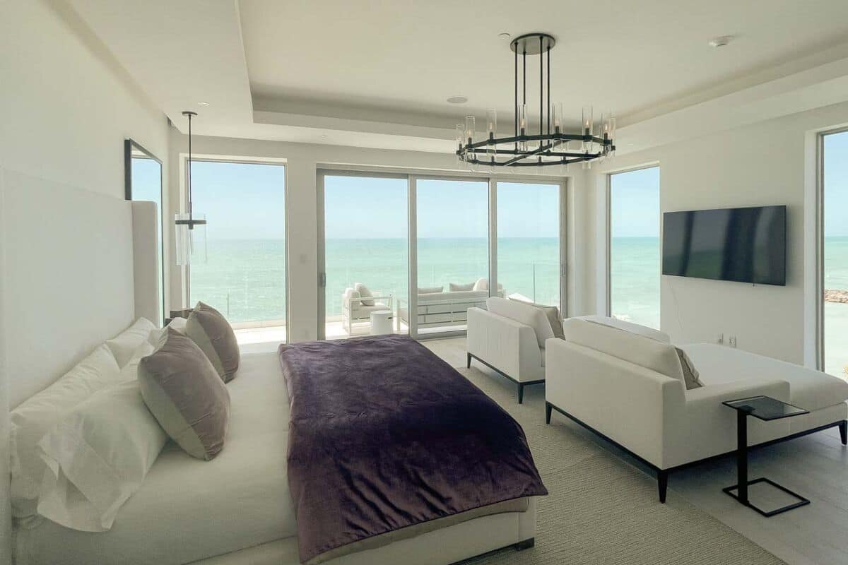 Een moderne hotelkamer met een groot bed, een bank, een televisie en een balkon met uitzicht op zee.