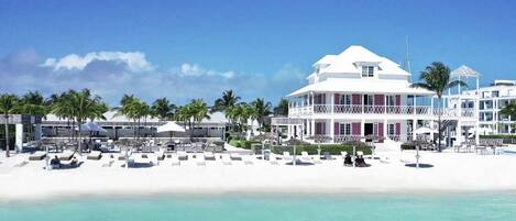 A beachfront hotel with multiple balconies, a pool area, and palm trees.