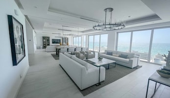 Una sala de estar moderna con un sofá grande, una mesa de centro y un comedor con vista al océano.