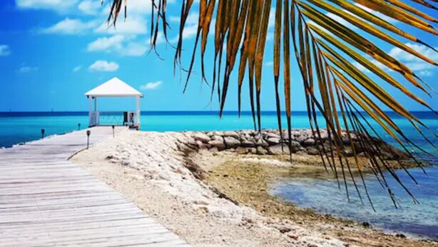 Une plage avec une promenade en bois menant à un kiosque blanc.