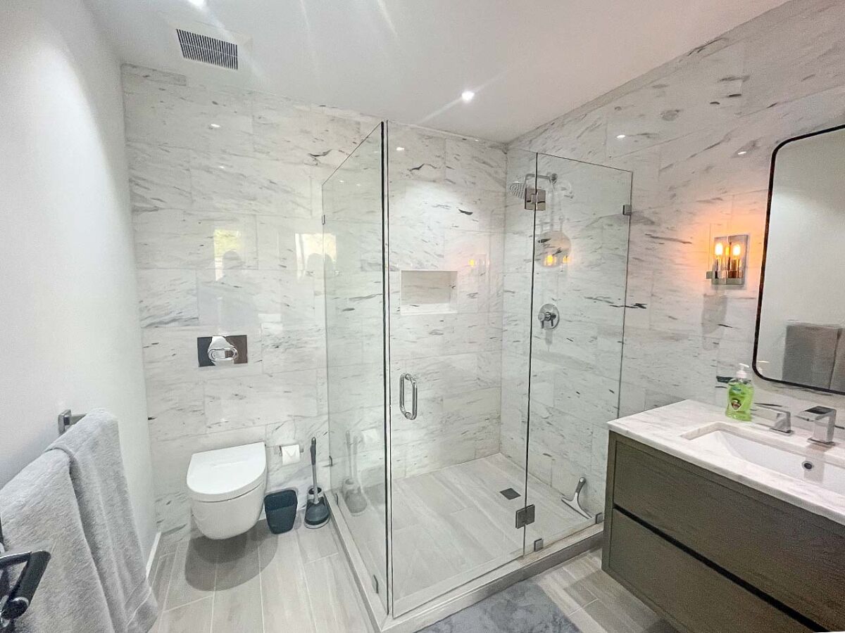 A modern bathroom with a glass-enclosed shower, a toilet, and a vanity with a sink.