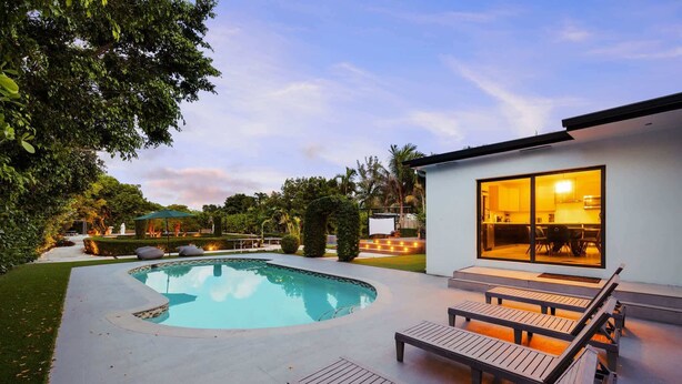 A modern house with a swimming pool, outdoor seating, and a well-maintained garden.
