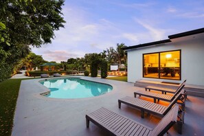 A modern house with a swimming pool, outdoor seating, and a well-maintained garden.
