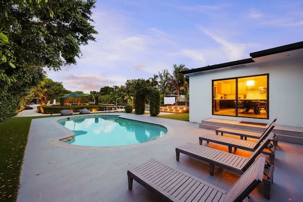 A modern house with a swimming pool, outdoor seating, and a well-maintained garden. - Swish Villa | Unique BKB Court | Outdoor Cinema (Miami)