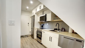 Een moderne keuken met witte kasten, roestvrijstalen apparatuur en een backsplash met een herringbone-patroon.