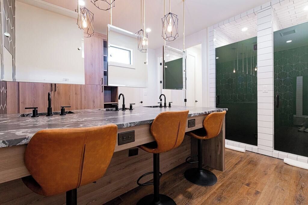 A modern kitchen with a marble countertop, wooden cabinets, and two bar stools.