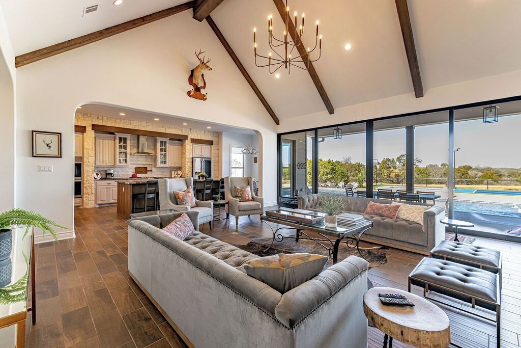 A spacious living area with a large sofa, a coffee table, and a view of a swimming pool.