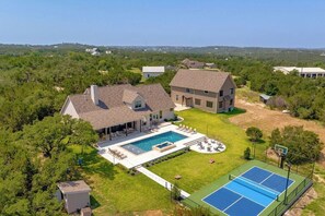 Propiedad residencial con piscina, cancha de tenis y una casa grande con un amplio patio trasero.