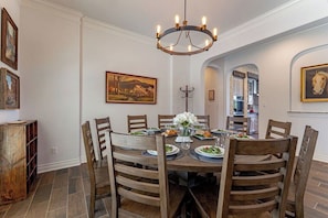 Comedor con una mesa redonda, sillas de madera y una lámpara de araña.