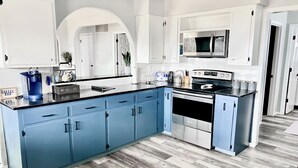 Een moderne keuken met blauwe kastjes, een roestvrijstalen fornuis en een magnetron.
