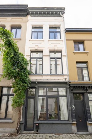 Une rangée de maisons de ville avec de grandes fenêtres et une porte noire.